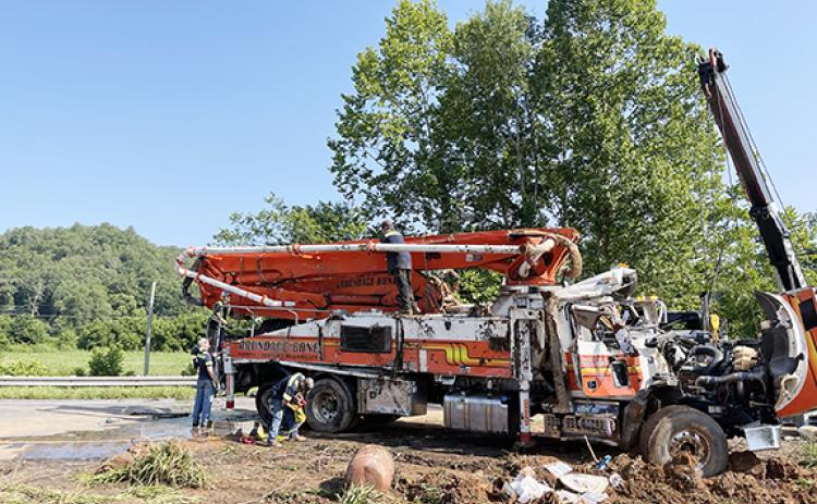 Photos by Randy Foster/editor@cherokeescout.com Wrecker operators disconnect lines from the wreckage of a concrete pumper truck that rolled over near Tomotla early Monday morning. 