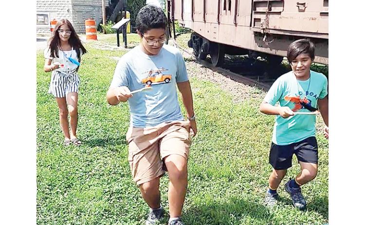 Gabriela, David and Santiago Barillas competed in the tomato relay race at the Murphy Farmers Market. David (center) took the first-place ribbon, while Gabriela (left) took second place and Santiago (right) walked away with third Saturday.