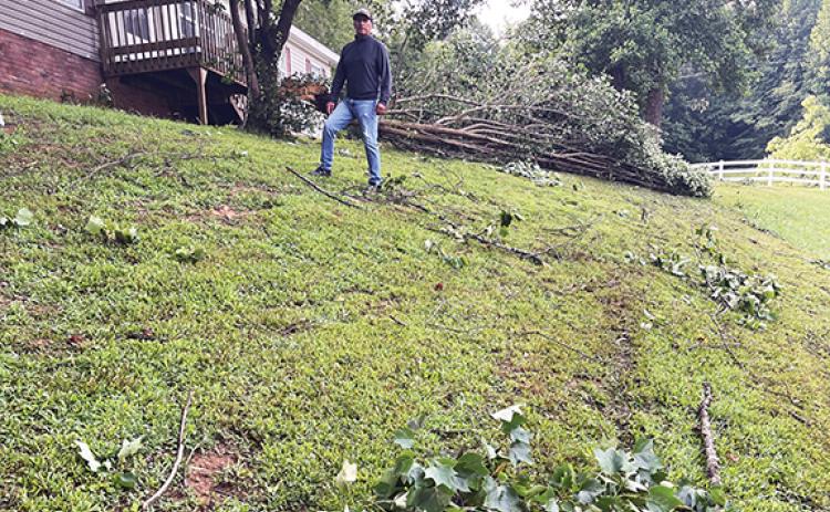 Randy Foster/editor@cherokeescout.com Cecelia Rosales Tinoco stands in his yard on the 1300 block of Fairview Road on Tuesday morning, taking stock of fallen branches and uprooted trees in his yard after a powerful storm swept through the area Monday.