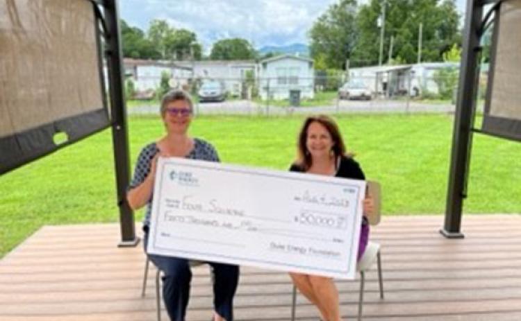 Lisa Leatherman (left), manager of government and community relations with Duke Energy, shows off the $50,000 grant award with Dr. Sue Lynn Ledford, executive director of Four Square Community Action.
