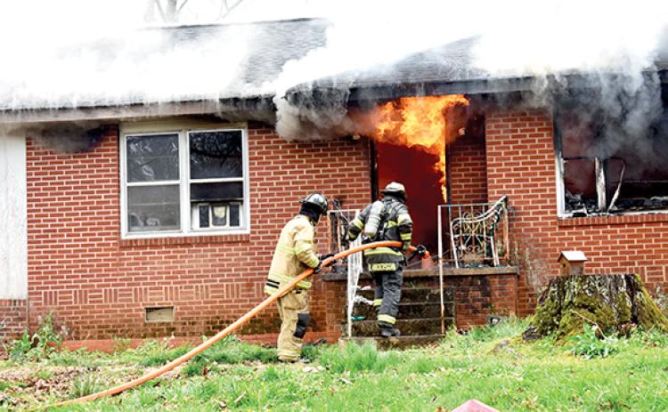 Becky Long/Clay County Progress Firefighters move in closer to assess the situation amid smoldering eaves and flames still billowing from the interior front entrance way and window on April 1. The fire was contained, but the house was most likely destroyed from the damages.